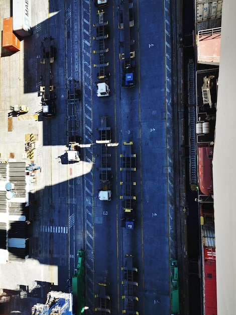 An aerial view of a busy distribution center with trucks efficiently loading and unloading cargo, supported by AI-powered route optimization technology.