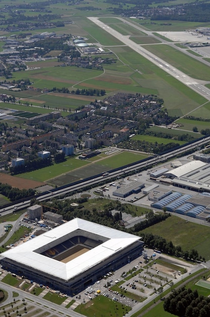 An aerial view of a distribution center in the United States with solar panels on the roof and electric delivery trucks lined up ready for dispatch, highlighting the integration of sustainable practices within logistics operations.