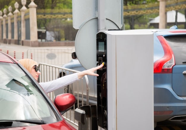 A close-up of an electric vehicle charging port being plugged into a delivery van at a distribution center. The background shows several other vans also being charged.