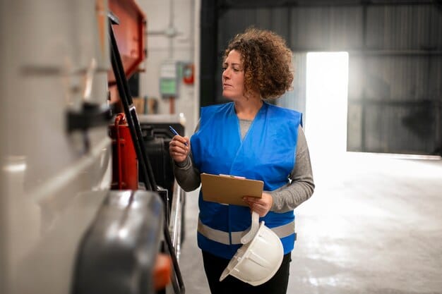 A close-up view of a technician inspecting the charging port of an electric delivery van. The technician is wearing a safety vest, and a charging station is visible in the background.