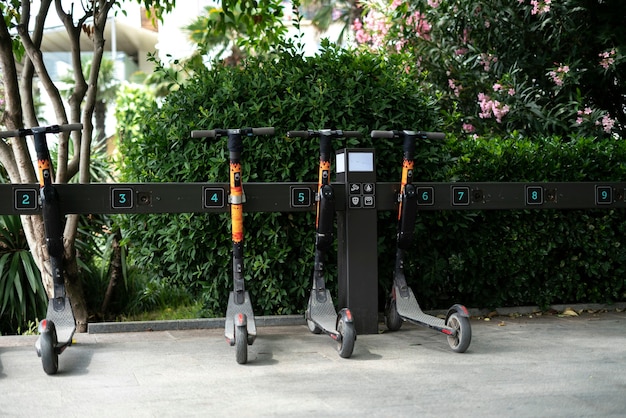 A close-up shot of a docking station with several shared electric scooters neatly parked, showing the QR code and instructions for unlocking and renting a scooter. This illustrates the ease of use and accessibility of micro-mobility services.