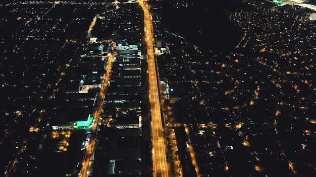 An aerial photograph of a city at dusk, showcasing a network of well-lit roads and parking garages. The scene is vibrant and modern, with clear indications of smart parking availability displayed via digital signs.