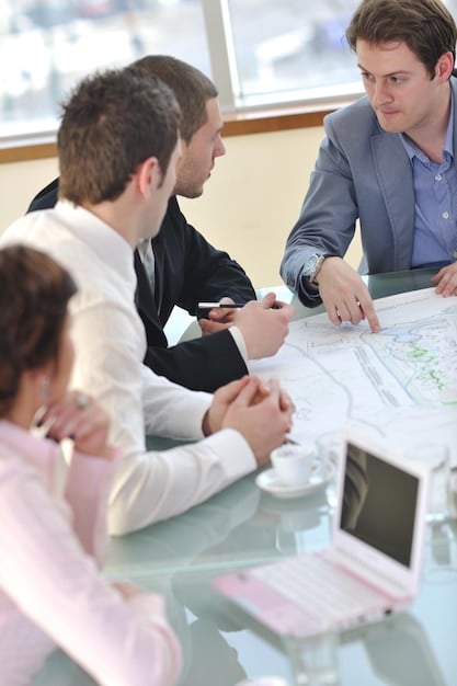 A group of city officials and private sector representatives meeting around a table, reviewing blueprints and discussing a smart city project proposal.