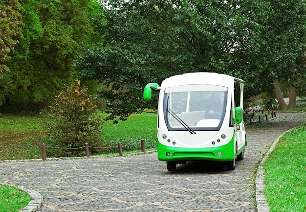 An image of a modern electric bus driving through a green urban area with trees lining the street, symbolizing the environmental benefits and sustainability of public transportation.