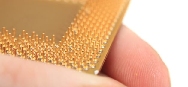 A close-up photo focusing on a semiconductor chip being placed on a circuit board in a cleanroom environment. The image highlights the intricate details of the chip and the precision required in its assembly.