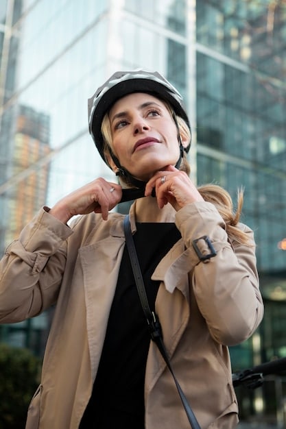A close-up of a person wearing a helmet while riding an e-scooter on a designated bike lane in a city. The focus is on the safety equipment and the rider following traffic rules.