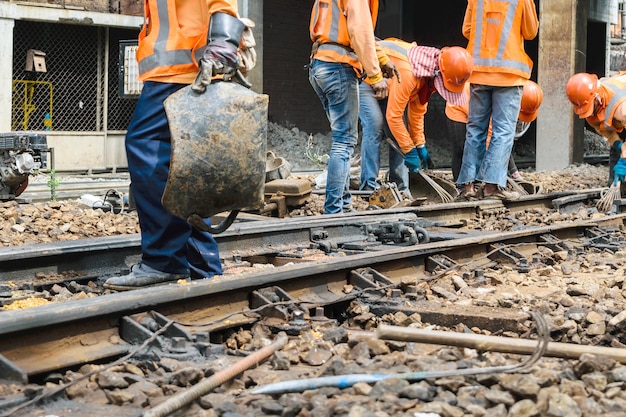 Close-up shot of construction workers building a new section of a high-speed railway track. The focus is on the workers' precision and teamwork, with heavy machinery visible in the background. The tone is industrious and forward-looking.