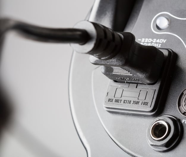 A detailed close-up of an electric vehicle's charging port, with the charging cable plugged in. The car's body is a bright, futuristic silver, and the background is slightly blurred to focus on the charging process. The charging port has various indicator lights showing the charging status.
