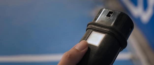 A close-up shot of an EV charging connector being plugged into an electric vehicle. The focus is on the connector and the charging port, with a blurred background showing the EV and the charging station.